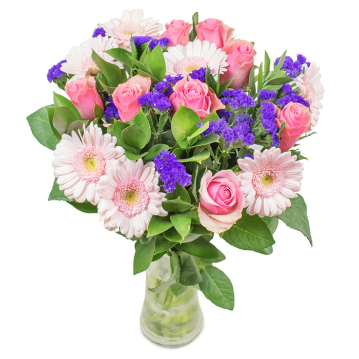 Artfully arranged in a clear glass vase, this striking bouquet-prepared in the heart of New Addington-features 7-9 rich pink roses, their petals in varying stages from tightly furled to gently opening, each exuding a sense of affection and classic beauty. They are softened by 5-7 pale pink gerbera daisies, distinguished by their expansive, radiating petals and subtle creamy centres, echoing the pastel hues of New Addington's open spaces at sunrise. Strikingly interwoven throughout the bouquet, clusters of deep purple statice or limonium serve both as an eye-catching accent and a textural counterpoint, their papery detail and vibrant shade reminiscent of wildflowers scattered across Addington Park. Lush, verdant greenery creates a generous, abundant base, providing both depth and a sense of freshly gathered nature. The transparent vase reveals clean stems and fresh water, reinforcing the impression of just-picked blooms perfect for prompt, same-day delivery around New Addington. Ideal for special occasions-birthdays, anniversaries, or Mother's Day-or even to brighten an office along King Henry's Drive, this arrangement, designed by experienced New Addington florists, is a radiant expression of joy, celebration, and heartfelt connection.